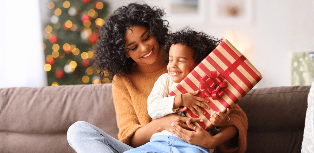Mother and child holding a holiday gift at home.